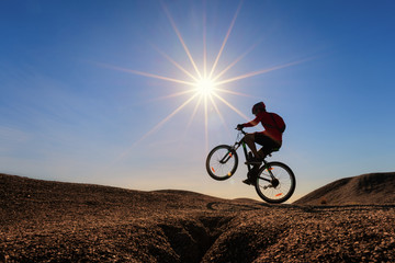 Fototapeta na wymiar Cyclist riding mountain bike on the rocky trail at sunset.