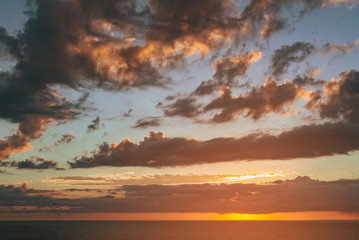 Obraz premium beautiful dramatic sunset over the sea with massive clouds. toned