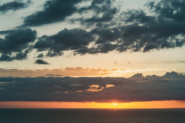 Naklejka na ściany i meble beautiful dramatic sunset over the sea with massive clouds. toned