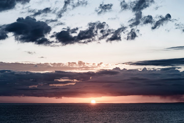 Fototapeta premium beautiful dramatic sunset over the sea with massive clouds. toned