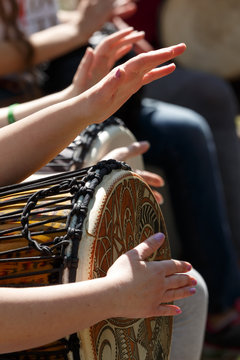 close-up of people's hands playing on African djembe drums on a sunny summer day. group of people with African drums musical instrument
