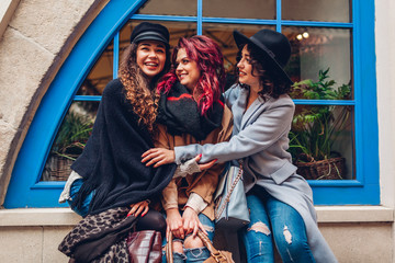 Young women hugging and laughing on city street. Best friends having good time together