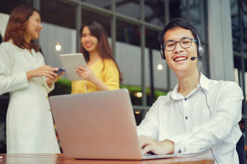Fototapeta premium close up asian call center man smiling with teamwork meeting behind at office 