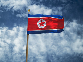 North Korea flag Silk waving flag of North Korea made transparent fabric with wooden flagpole gold spear on background blue sky white smoke clouds real retro photo Countries of world 3d illustration