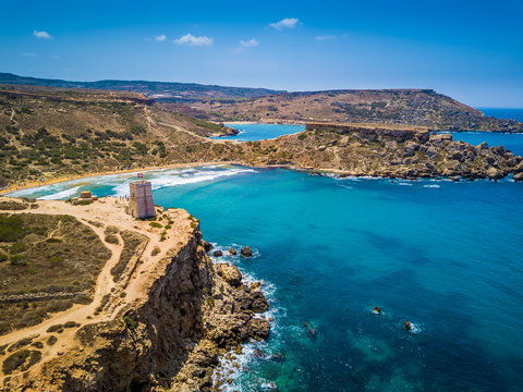 Ghajn Tuffieha, Malta - Beautiful Ghajn Tuffieha Bay, Ghajn Tuffieha Watch Tower and Riviera beach from above on a bright summer day with Gnejna Bay and blue sky at background