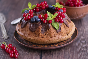 Homemade chocolate cake with chocolate icing, mint  and fresh berries.