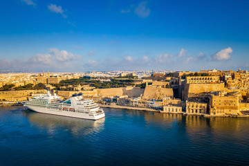 Valletta, Malta - Cruise ship in the Grand Harbor at sunrise with the ancient city of Valletta at background