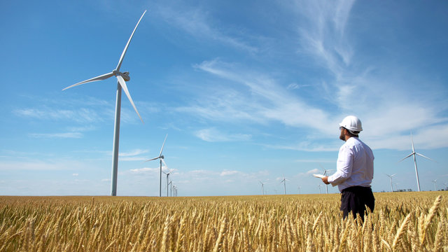 Worker of a wind power plant in a yellow wheat field