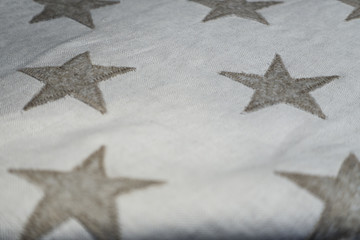 Fototapeta na wymiar Gray stitched stars on herringbone pattern fabric