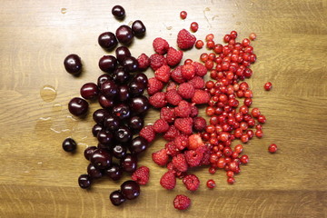 Photo of cherry, red currant and raspberries on wooden table