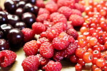 Photo of cherry, red currant and raspberries on wooden table