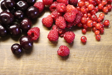 Photo of cherry, red currant and raspberries on wooden table