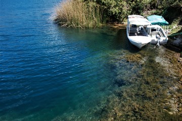 Tour boats docked at shoreline over steep drop off into Laguna Cuicocha Ecuador