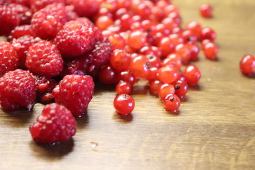 Photo of red currant and raspberries on wooden table