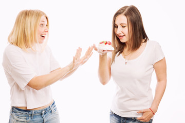 Two young women are eating a cake, close-up