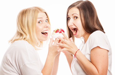 Two young women are eating a cake, close-up