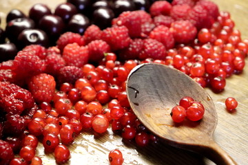Photo of cherry, red currant and raspberries on wooden table