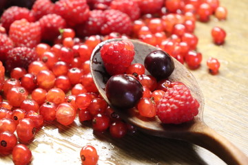 Photo of cherry, red currant and raspberries on wooden table