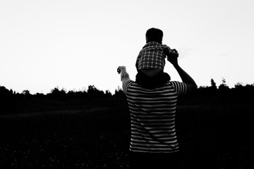 Obraz premium Father and son playing in the field at sunset time. Family having fun on summer vacation