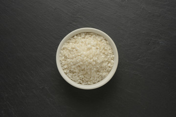 Arroz blanco redondo en un cuenco de cerámica blanca sobre un fondo negro de piedra