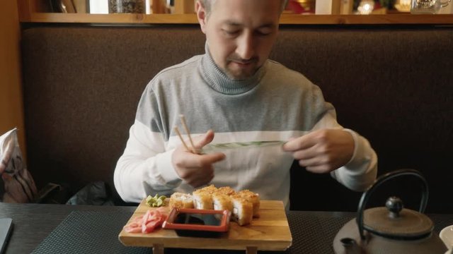 A man learns to use chopsticks for sushi. The man looks at the instructions from the sushi sticks. Hashi, chopsticks ohashi, varibasi - simple wooden hasi