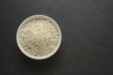 Arroz blanco redondo en un cuenco de cerámica blanca sobre un fondo negro de piedra