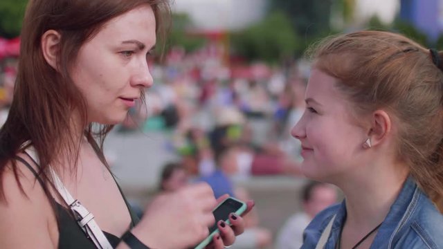 Young woman explains to girl which flag to paint on cheeck