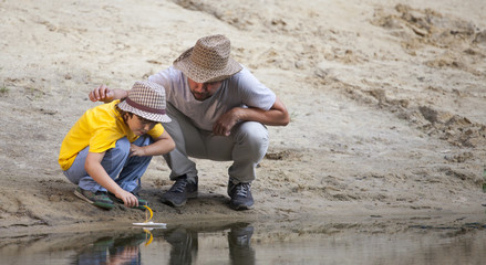 Fototapeta na wymiar Happy boy and father go fishing on the river, children with a fishing rod on the shore of the lake