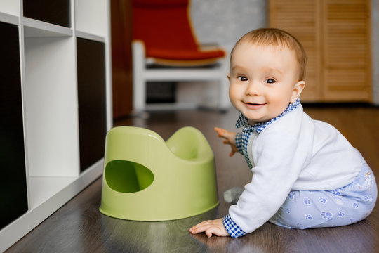 Portrait of a smiling baby sitting on the floor near his pottie