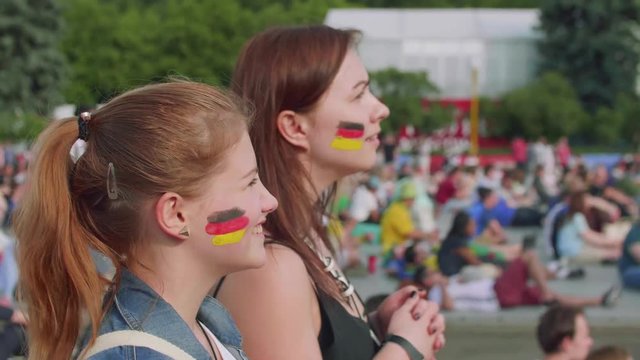 Girls cheer for German team during football match in fan zone