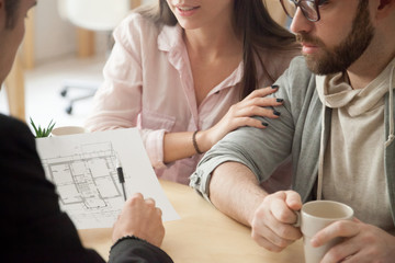 Close up of millennial couple visiting architect or designer office, consulting about future house project, young spouses deciding to buy first apartment or flat together or planning home renovation. - obrazy, fototapety, plakaty