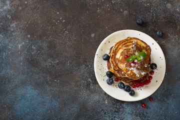 Pancakes and fresh berries on grunge stone background