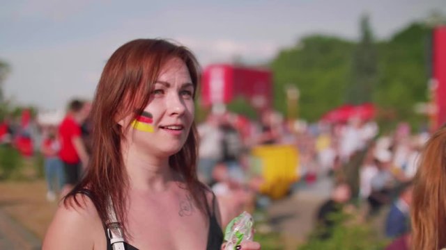 Young woman with german flag painted on cheeck is disappointed with game