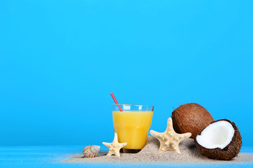 Coconuts with glass of juice on blue background