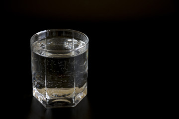 Glass with clear water on a black background