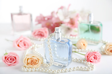 Perfume bottles with roses and beads on white background