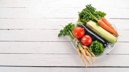 Fresh vegetables in a plate. Organic food. On a wooden background. Top view. Copy space.