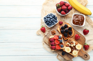 Toasts bread with berries on brown cutting board