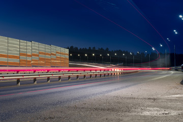 Large city road night scene, night car trails. Road with sound or acoustic barrier