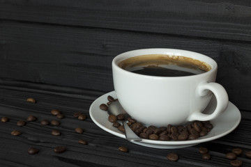 coffee in a white cup and coffee beans on a dark, wooden table