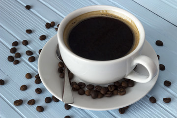 coffee in a white cup and coffee beans on a table