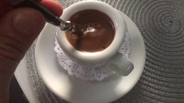 we stir a spoon of coffee in a white cup