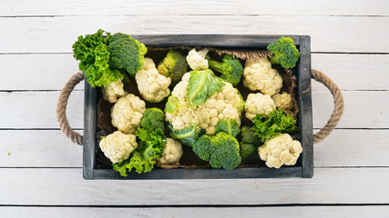 Cauliflower in a wooden box. Fresh vegetables. On a wooden background. Top view. Copy space.