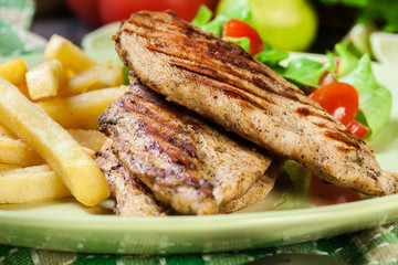 Grilled chicken breasts served with fries
