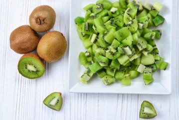 Freshly sliced kiwi fruit with whole kiwis in background.