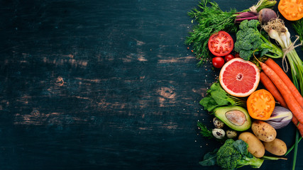 Healthy food. Vegetables and fruits. On a black wooden background. Top view. Copy space.