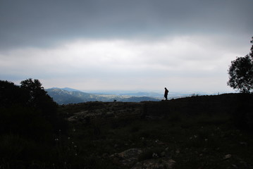 Silhouette of man on top of the mountain at sunrise or bending