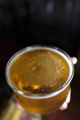 Hand holding a golden Beer Glass Drink in a black background pilser ale pale porter honey isolated beverage cup aroma alcohol liquid cockatil cold white brown refreshment
