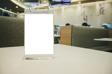 Mockup empty white label menu frame on table with cafe restaurant interior background