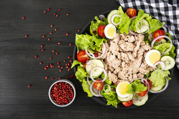 Salad with tuna, anchovies and vegetables. Mediterranean food. The background is black. Top view. Copy space. Horizontal shot.